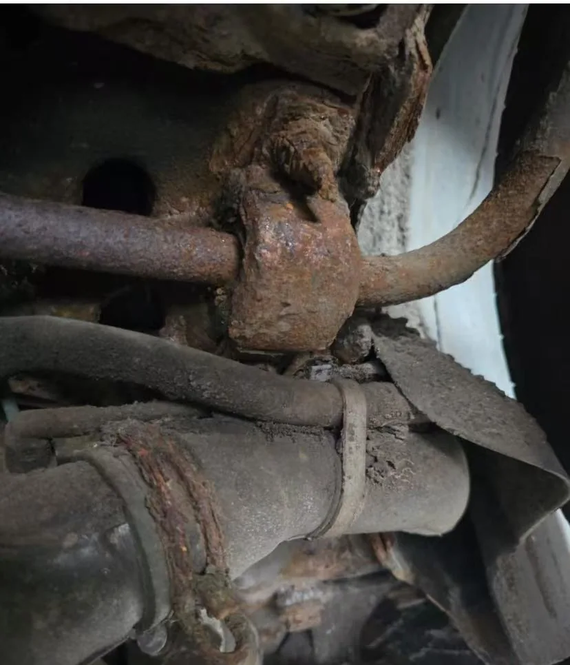 Corroded Peugeot anti-roll bar bearing clamp still mounted on the car, clamping the anti-roll bar to the body