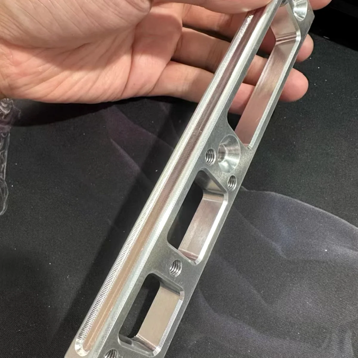 Machined aluminum bracket held in hand, reproduced by EKINSUN from a customer sample