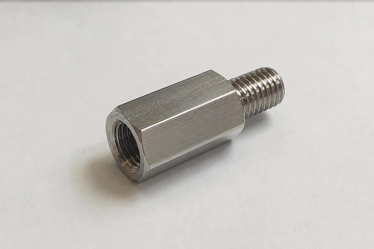 Custom stainless steel thread adapter with hex body, external UN male thread on one end and internal metric female thread on the other, machined by EKINSUN